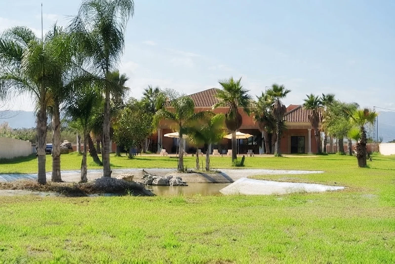El lago en primer plano y, detrás, la casa entre palmeras