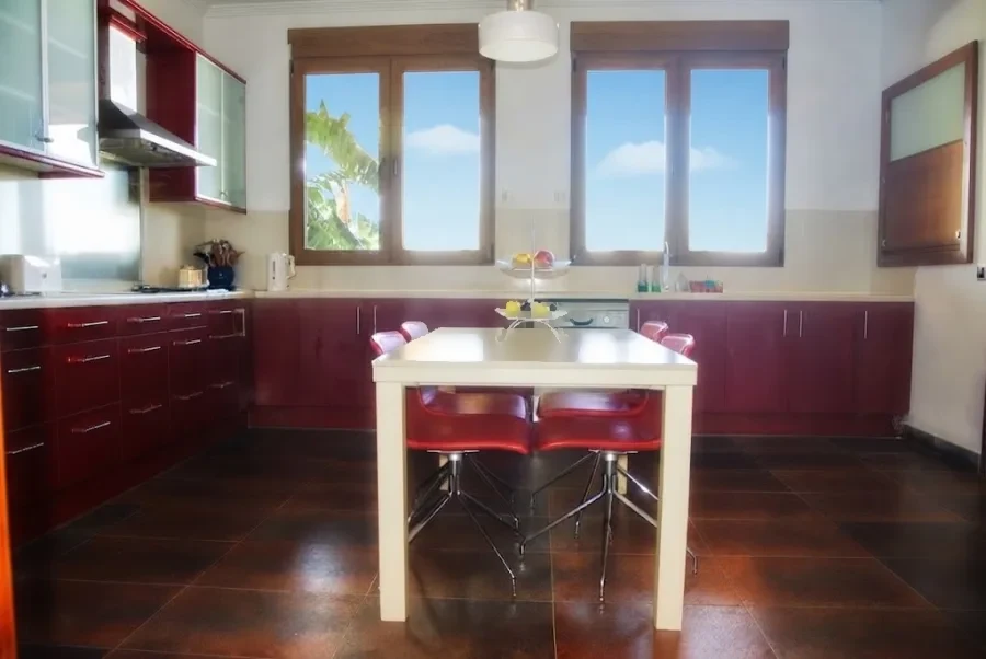 Cocina con mesa blanca y ventanas al jardín