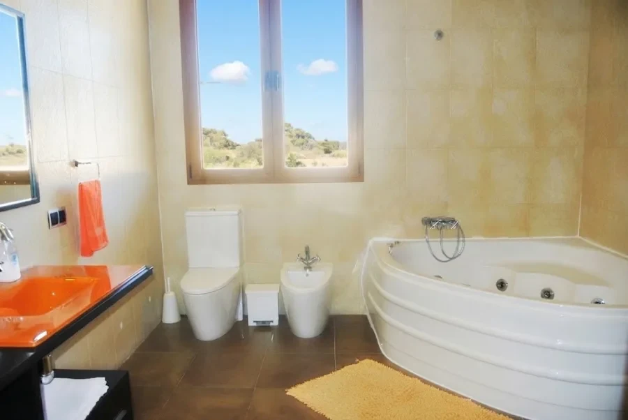 Baño con bañera de hidromasaje en esquina bajo la ventana